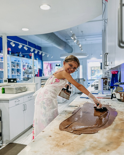 Kid girl working on making chocolate smiling at camera
