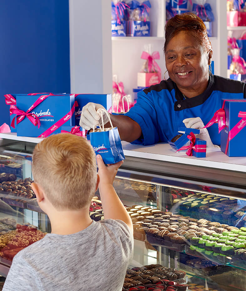 A woman giving a child a chocolate treat bag.