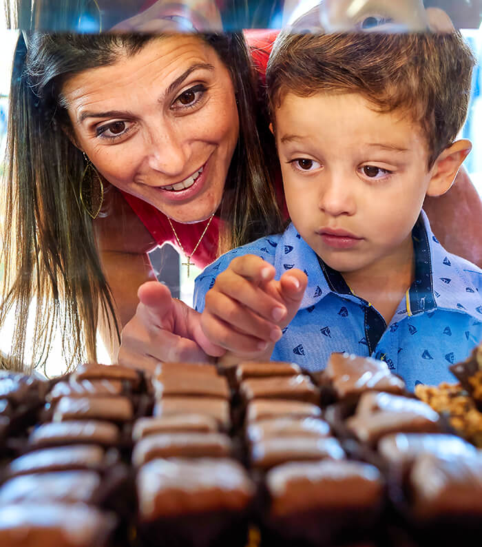 A woman and child overlooking a chocolate assortment.