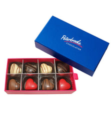 Open box of heart shaped chocolates with a blue lid featuring 'Peterbrooke Chocolatier' on a white background